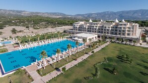 A large hotel with a swimming pool, multiple floors, and a view of mountains in the background. - Andriake Beach Club Hotel - All Inclusive  (Demre)