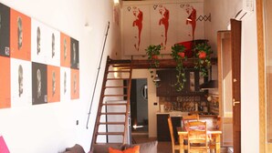 Ein gemütliches Wohnzimmer mit Holzboden, einer Treppe, einem Essbereich mit Holzmöbeln und einer Küche im Hintergrund.