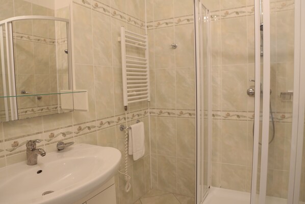 Une salle de bain avec une douche à parois de verre, un lavabo avec un miroir et un porte-serviettes.