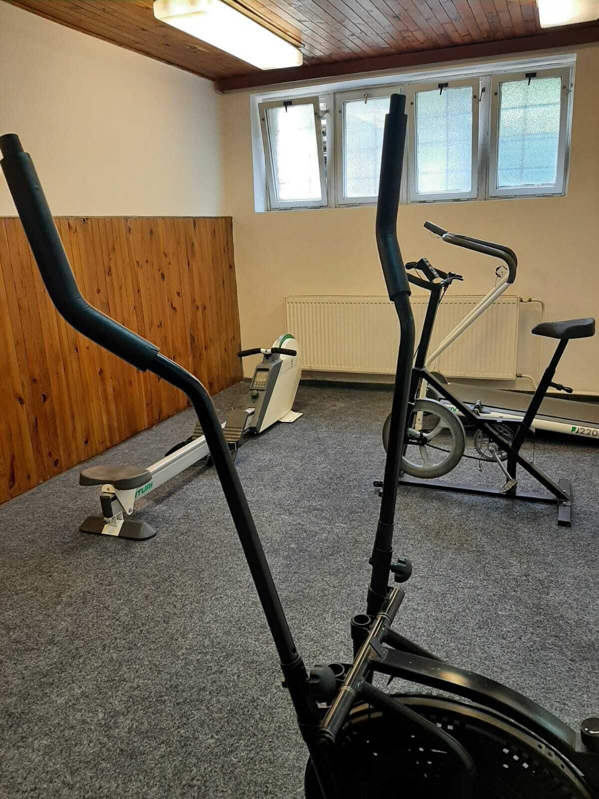A gym with exercise equipment including a stationary bike, a treadmill, and a rowing machine.