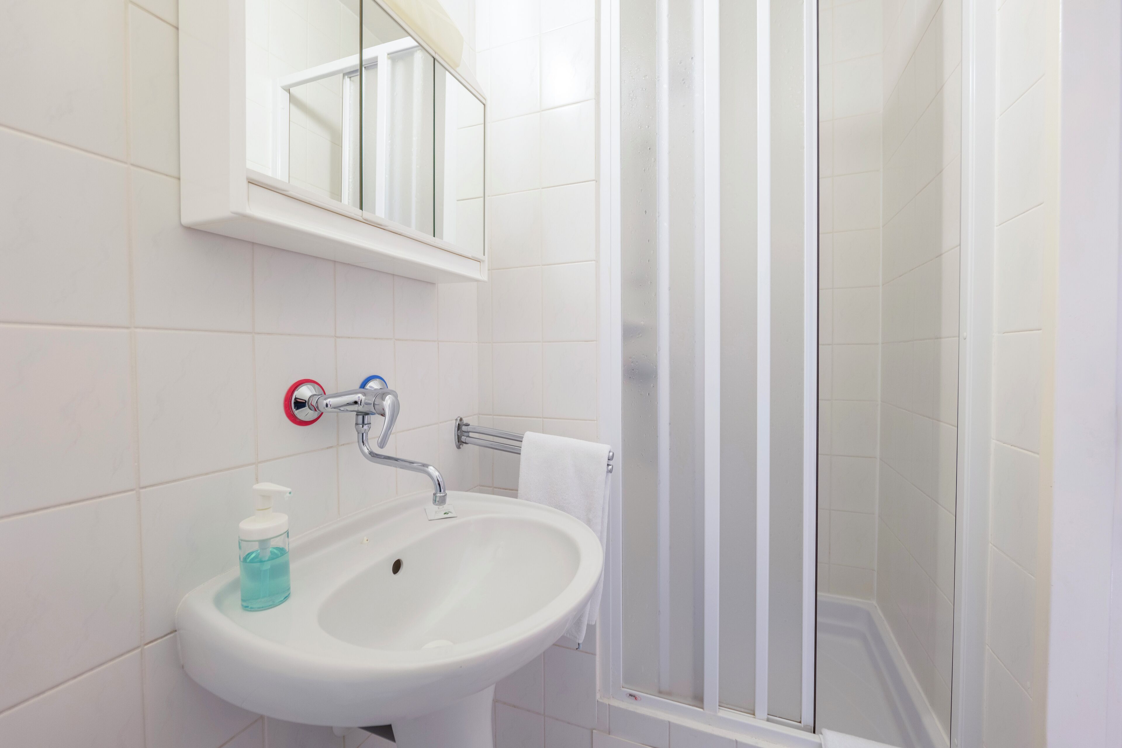 A bathroom with a white sink, a mirror, and a glass shower enclosure.