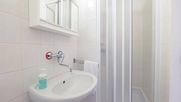 A bathroom with a white sink, a mirror, and a glass shower enclosure.