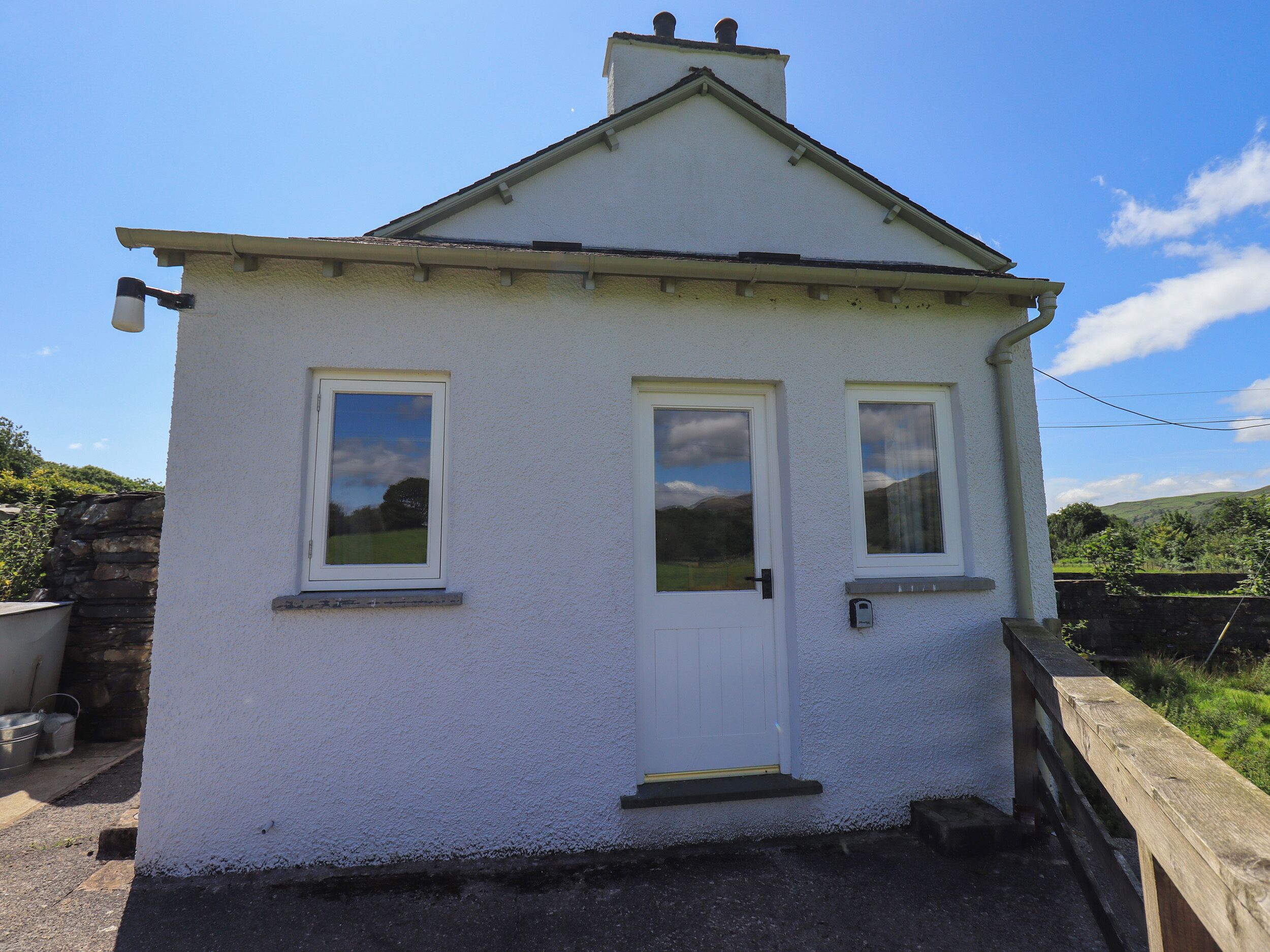 A small, single-story house with a white exterior, a front door, and two windows.