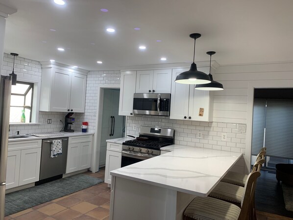 Enjoy cooking in this well-lit kitchen with a stove, microwave, and large window.