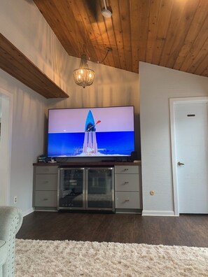 Relax in this stylish living room with a flat-screen TV, chandelier, and comfortable seating area.