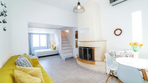 Ein modernes Wohnzimmer mit Sofa, Kamin, Esstisch und einer Treppe, die in eine obere Etage führt.