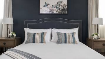 A neatly made bed with patterned pillows, a dark headboard, and a framed artwork above it.