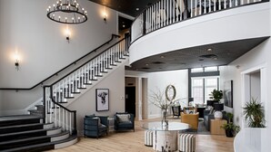 A spacious living area with a curved staircase, a round glass coffee table, and a seating arrangement. - The Federal (Brunswick)