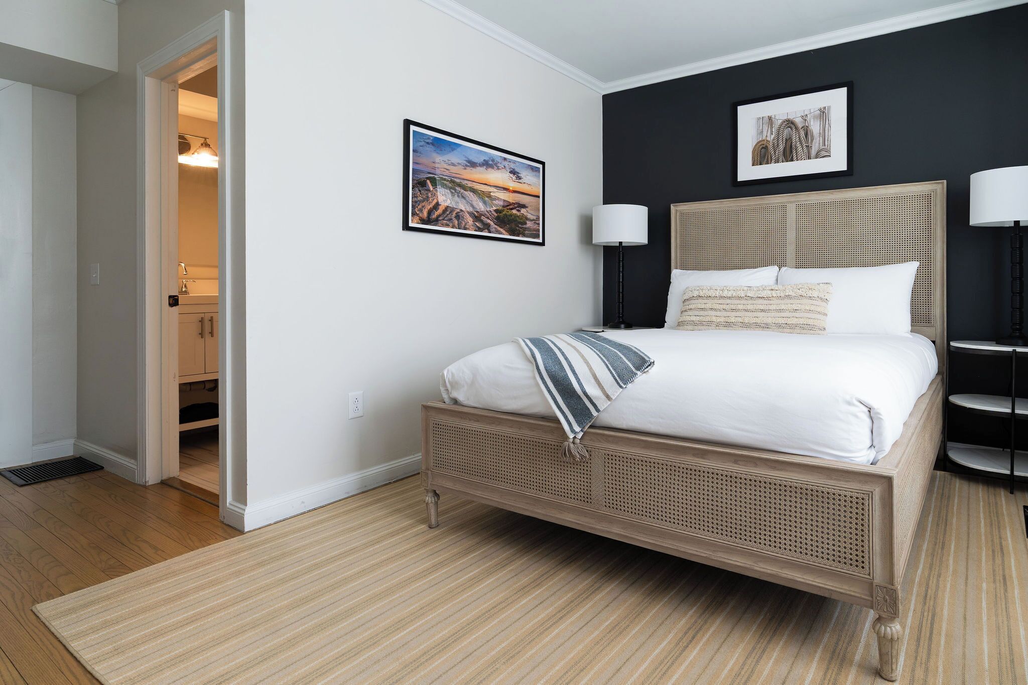 A bedroom with a bed, two wall-mounted lamps, and two framed pictures.