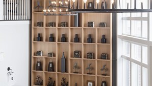 A modern interior with a curved reception desk, a wooden shelving unit with various decorative items, and a large window providing natural light. - The Federal (Brunswick)