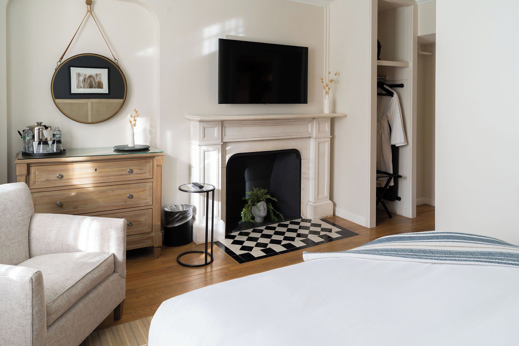 A bedroom with a bed, a dresser, a television above a fireplace, and a closet.
