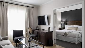 Una habitación de hotel moderna con una cama, un escritorio, una silla, un televisor y un sofá.