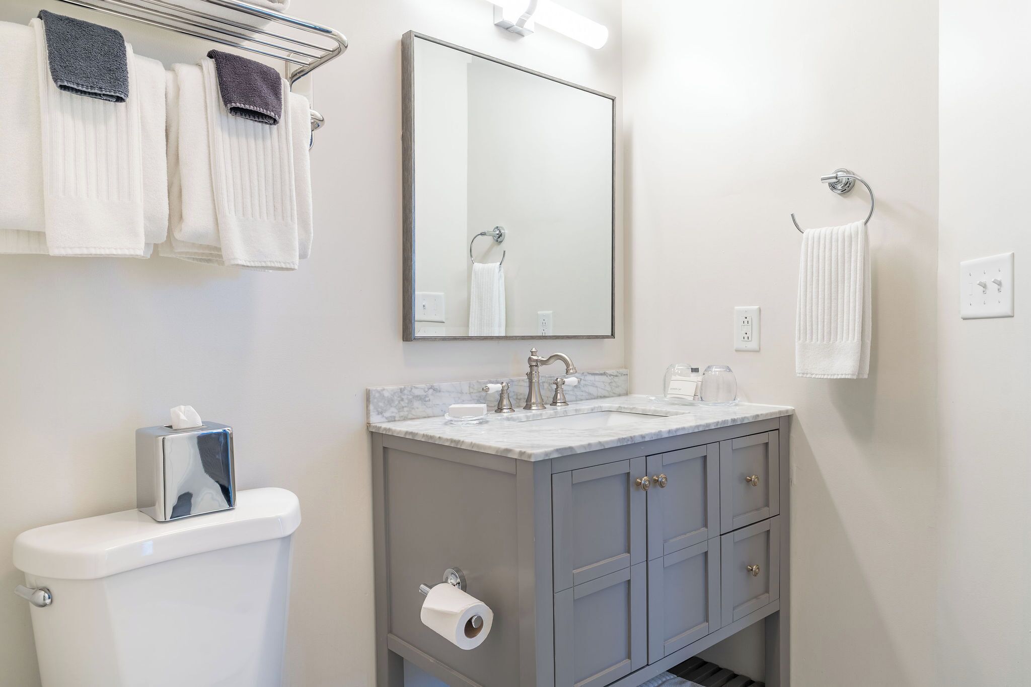 Une salle de bain équipée d’un WC, d’un lavabo, d’un miroir, d’un porte-serviettes et d’une serviette accrochée au mur.