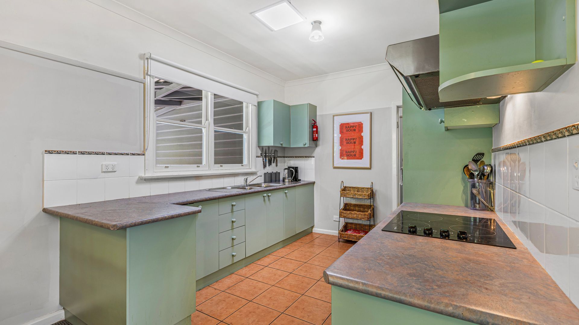 A compact kitchen with light green cabinets, a white countertop, and a tiled floor.