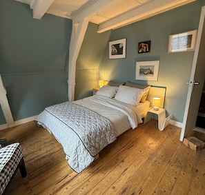 A bedroom with a bed, wooden flooring, and a nightstand with a lamp. - BB 1971 Hazenstraat (shared bathroom) (Amsterdam)