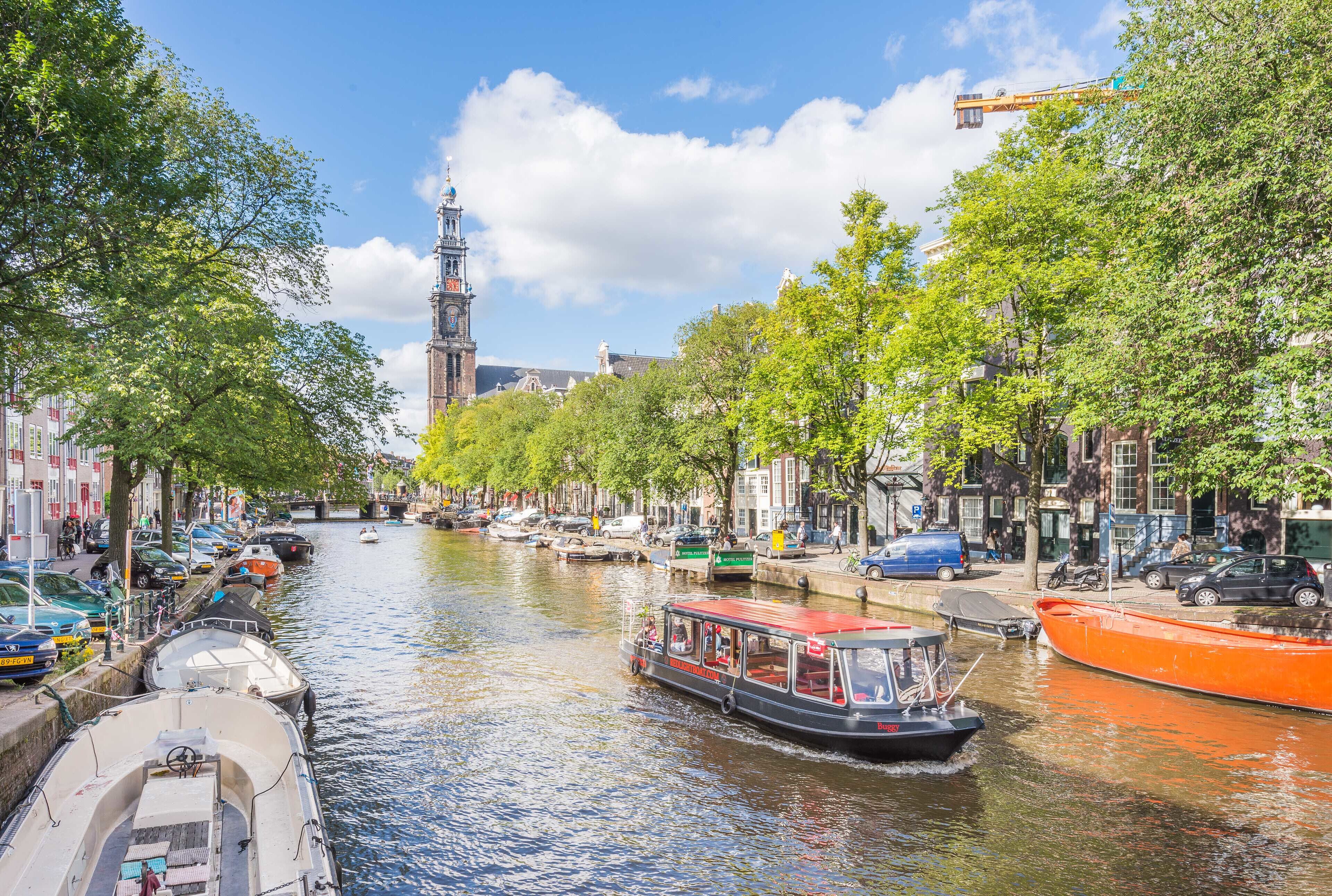 A canal with boats, a clock tower, and buildings along the water.
