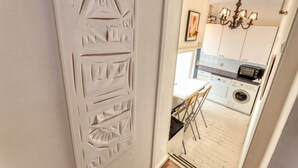 A narrow hallway leading to a kitchen with a washing machine, a toaster, and a chandelier. - BB 1971 Hazenstraat (shared bathroom) (Amsterdam)