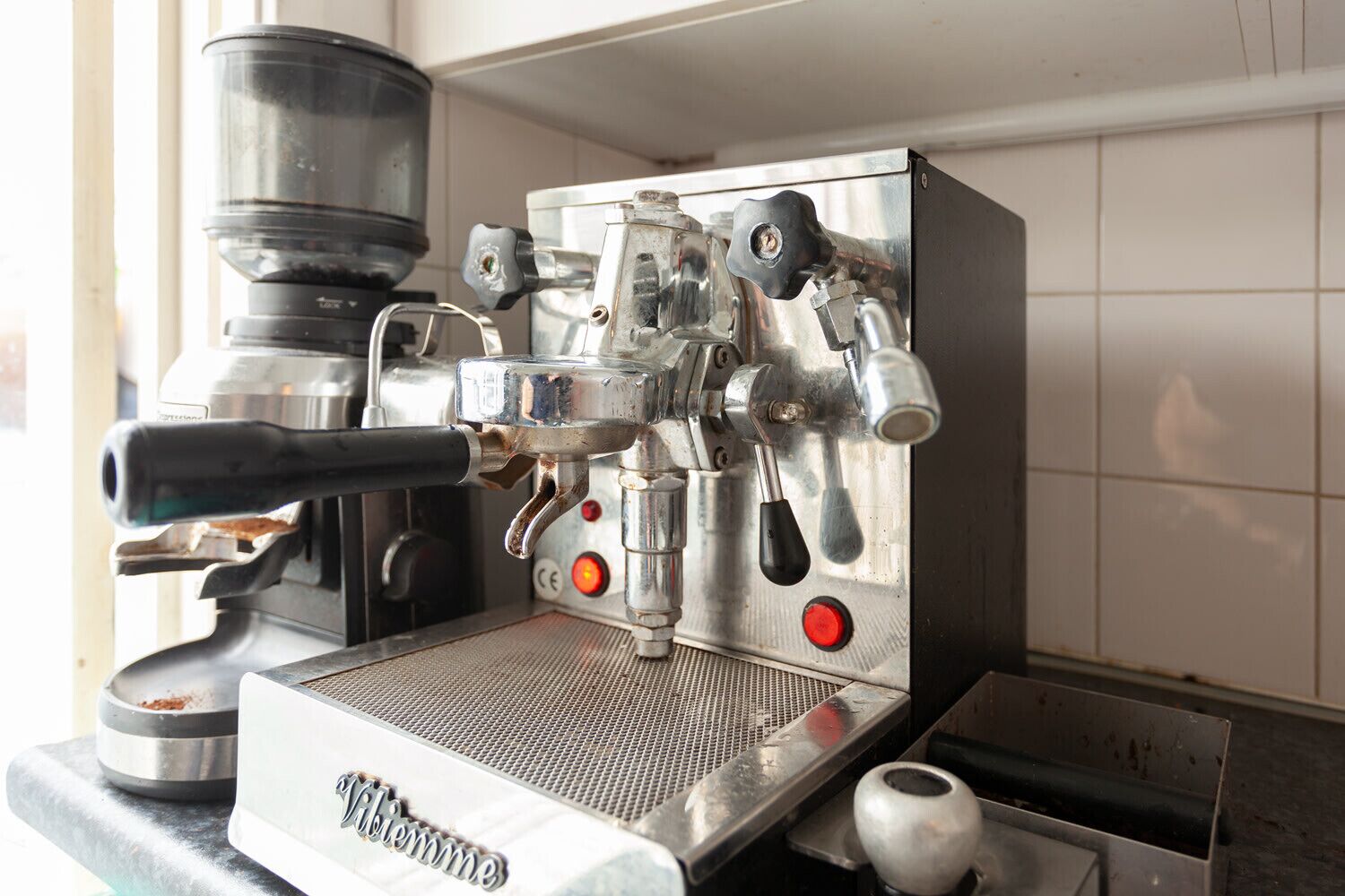 Eine Kaffeemaschine mit einer Metallplatte, einer Bedienblende mit Tasten und einem Becherhalter.