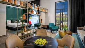 A modern living room with a sofa, chairs, a TV, and a large window. - Hotel Botanica- Limited Edition By Fattal (Haifa)
