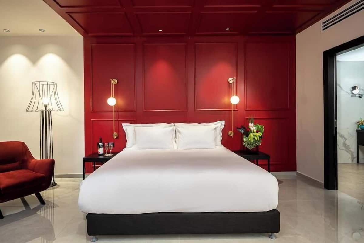 Un dormitorio moderno con una cama grande, paredes rojas y dos lámparas de noche.