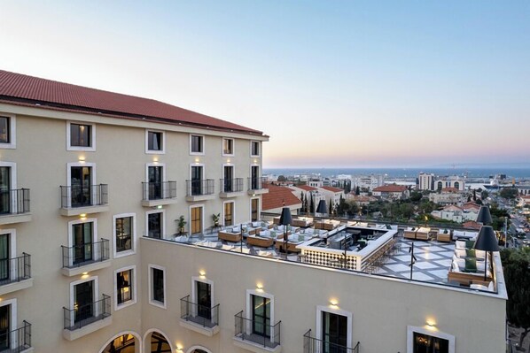 A multi-story hotel with balconies, outdoor seating, and a cityscape view. - Hotel Botanica- Limited Edition By Fattal (Haifa)