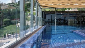 A rooftop infinity pool with glass railings, a canopy, and a view of the cityscape. - Hotel Botanica- Limited Edition By Fattal (Haifa)
