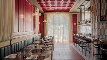 A restaurant with a long counter, booths, and a bar area.
