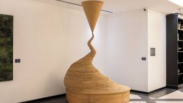 Una instalación de arte moderno en un vestíbulo con diseño espiral, suelo de madera y una gran pintura abstracta en la pared.