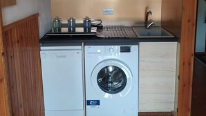 A compact kitchen with wooden cabinets, a washing machine, and a sink.