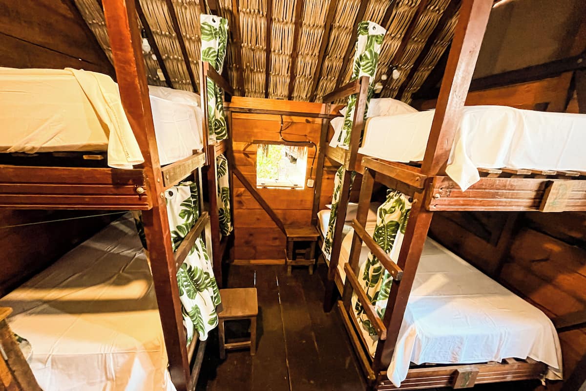 Eine Holzhütte mit Etagenbetten, jedes mit einem kleinen Tisch und einem Stuhl.
