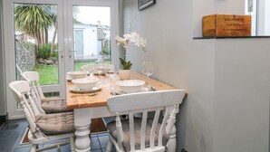 A dining area with a wooden table set for four, white chairs, and a glass door leading to a garden. - 6 Milton Place (Bideford)