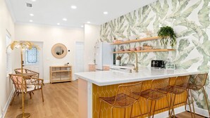 A modern kitchen with a central island, wooden chairs, and a decorative mirror. - Luxury Villa, 2.5 Blocks from the Beach, Hot Tub, Outdoor Oasis, Mini Putt, Arcade games and so much more. (Cape Canaveral)