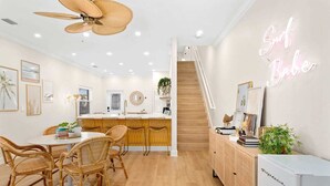 A modern kitchen with a central island, wooden flooring, and a neon sign reading "Surf Babe". - Luxury Villa, 2.5 Blocks from the Beach, Hot Tub, Outdoor Oasis, Mini Putt, Arcade games and so much more. (Cape Canaveral)