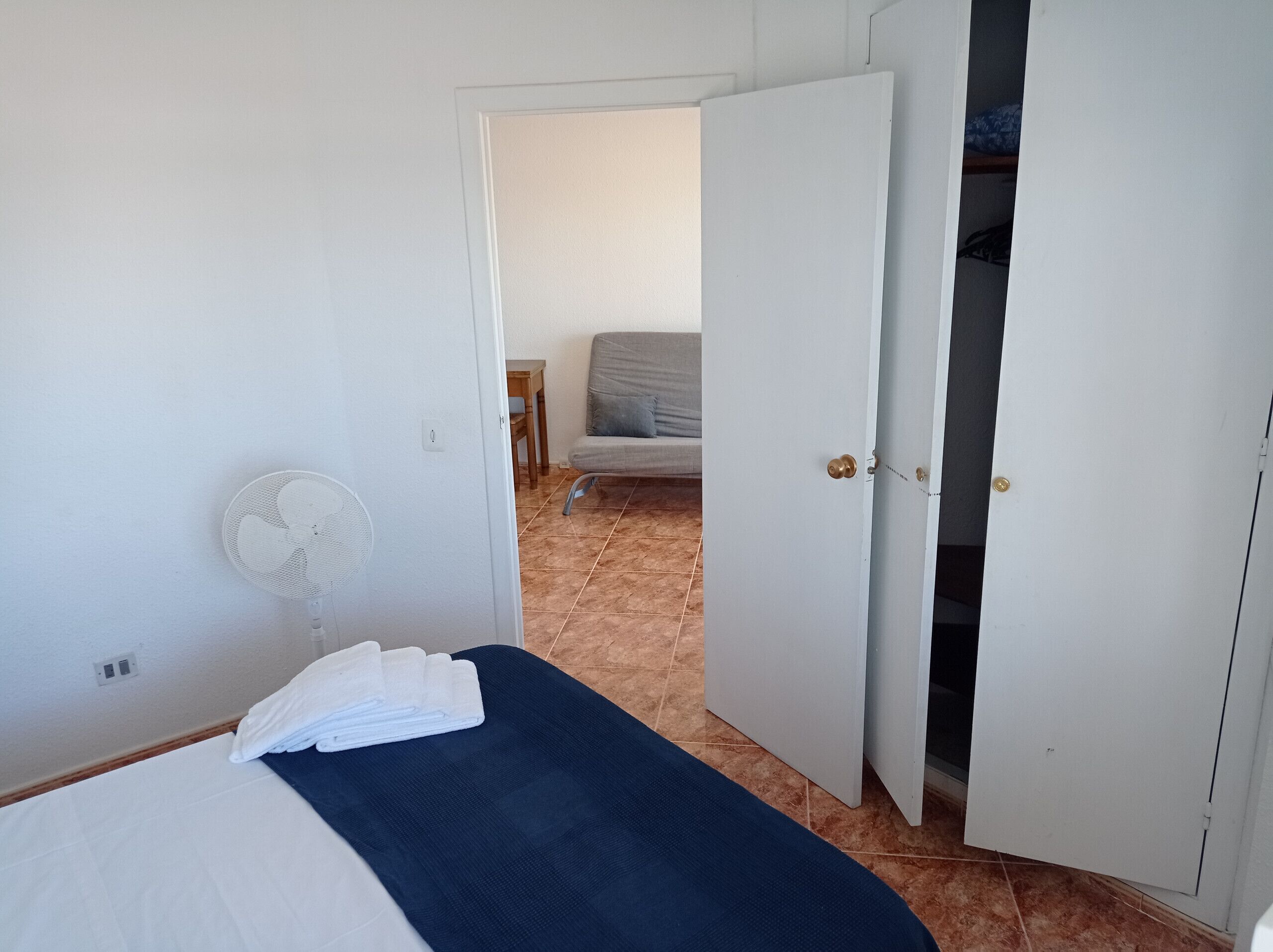 Ein Schlafzimmer mit einem Bett, einem Ventilator und einem Kleiderschrank.