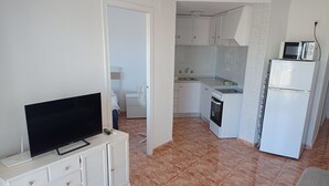 Una cocina compacta con televisor, microondas y refrigerador.