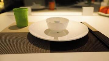 A table with a white plate, a green cup, and a black chopstick set.