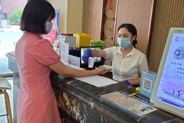 A reception desk with a computer, a QR code, and informational posters. - Lanting Wanpan Hotel (Changsha)
