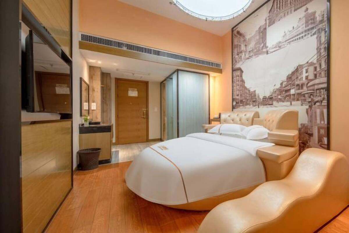 Quarto de hotel moderno com uma cama grande, uma toucador e vista para o horizonte da cidade.