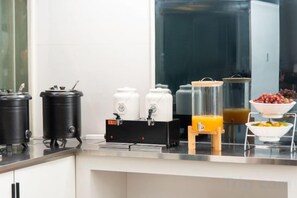 Eine Küchenzeile mit Kaffeemaschine, Saftspender und Obstschale.