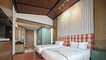A hotel room with two beds, a wooden ceiling, a checkered headboard, and a small cabinet.