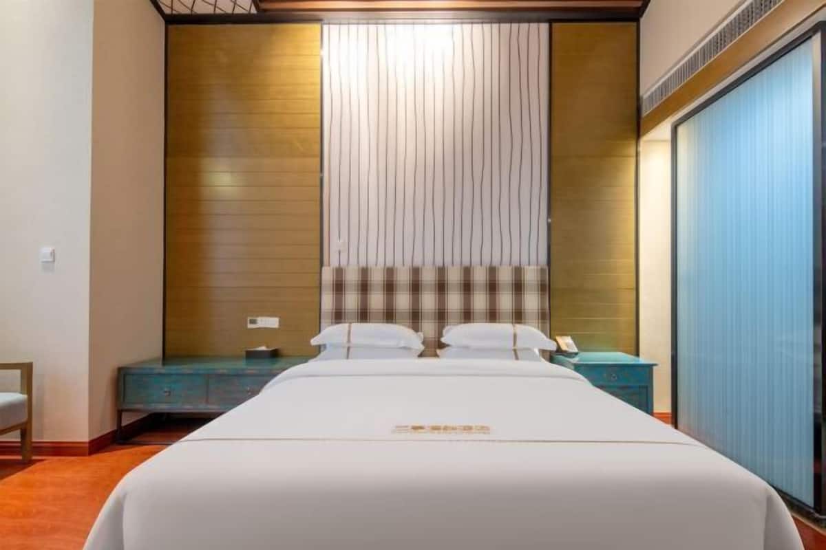 Quarto de hotel com uma cama grande, uma parede de destaque em madeira, um painel de cabeceira xadrez e um armário azul.