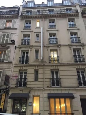 A multi-story building with balconies, large windows, and a sign indicating a business on the ground floor. - PAX HOTEL (Paris)
