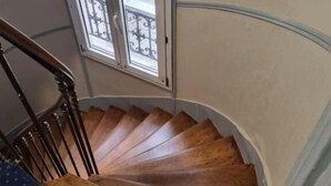 Un escalier en colimaçon en bois, doté d’une rampe en verre et d’une fenêtre située au-dessus.