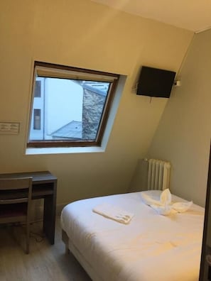 A bedroom with a bed, a desk, a chair, a window, and a TV. - PAX HOTEL (Paris)