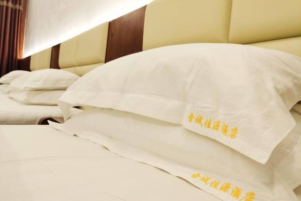 A neatly made bed with white linens and pillows, and a headboard with a wooden panel.