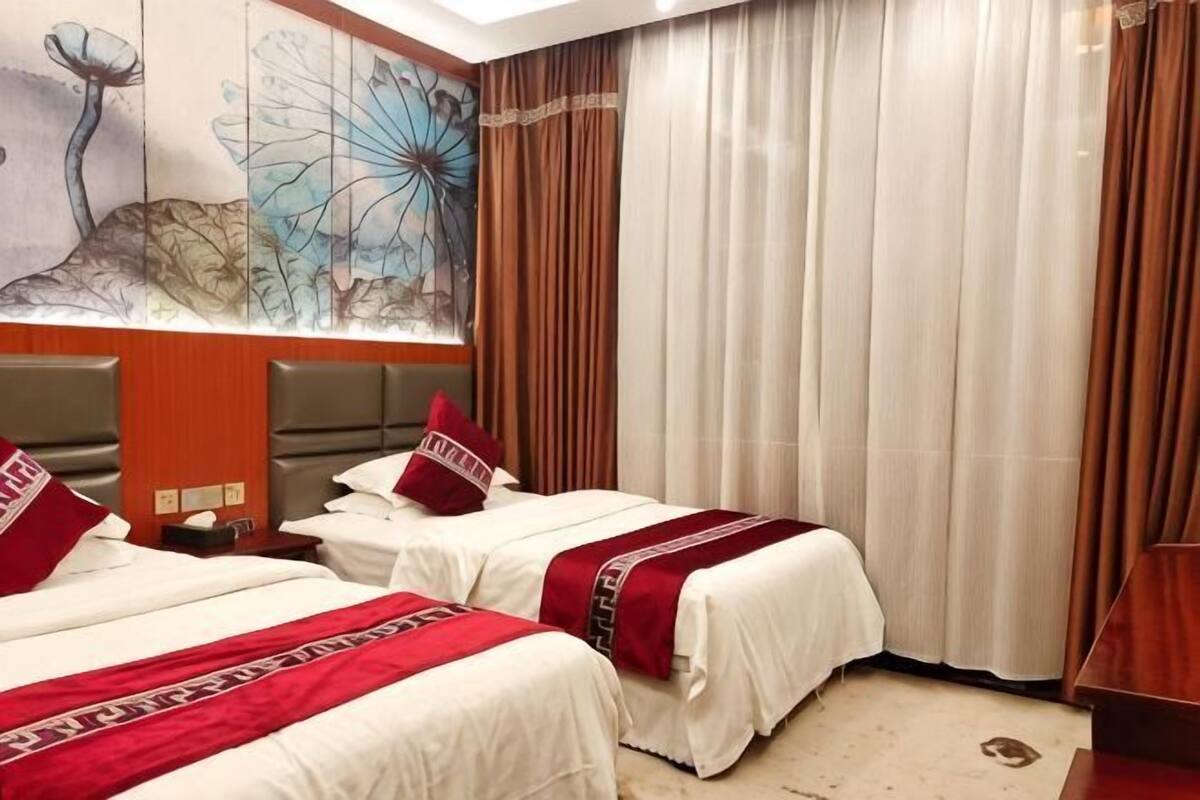 A hotel room with two beds, a large window with curtains, and a wall mural.