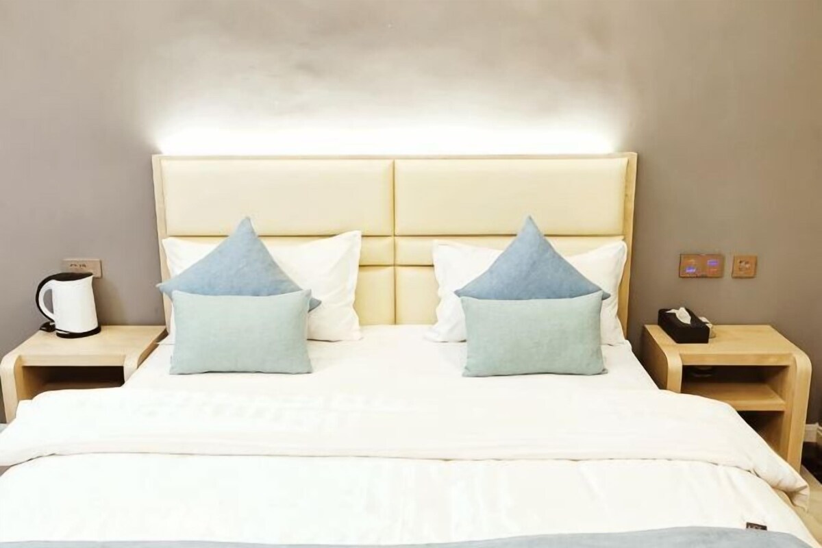 Una camera d'albergo con un letto grande, due comodini, un tavolino, una macchina del caffè e un telefono.