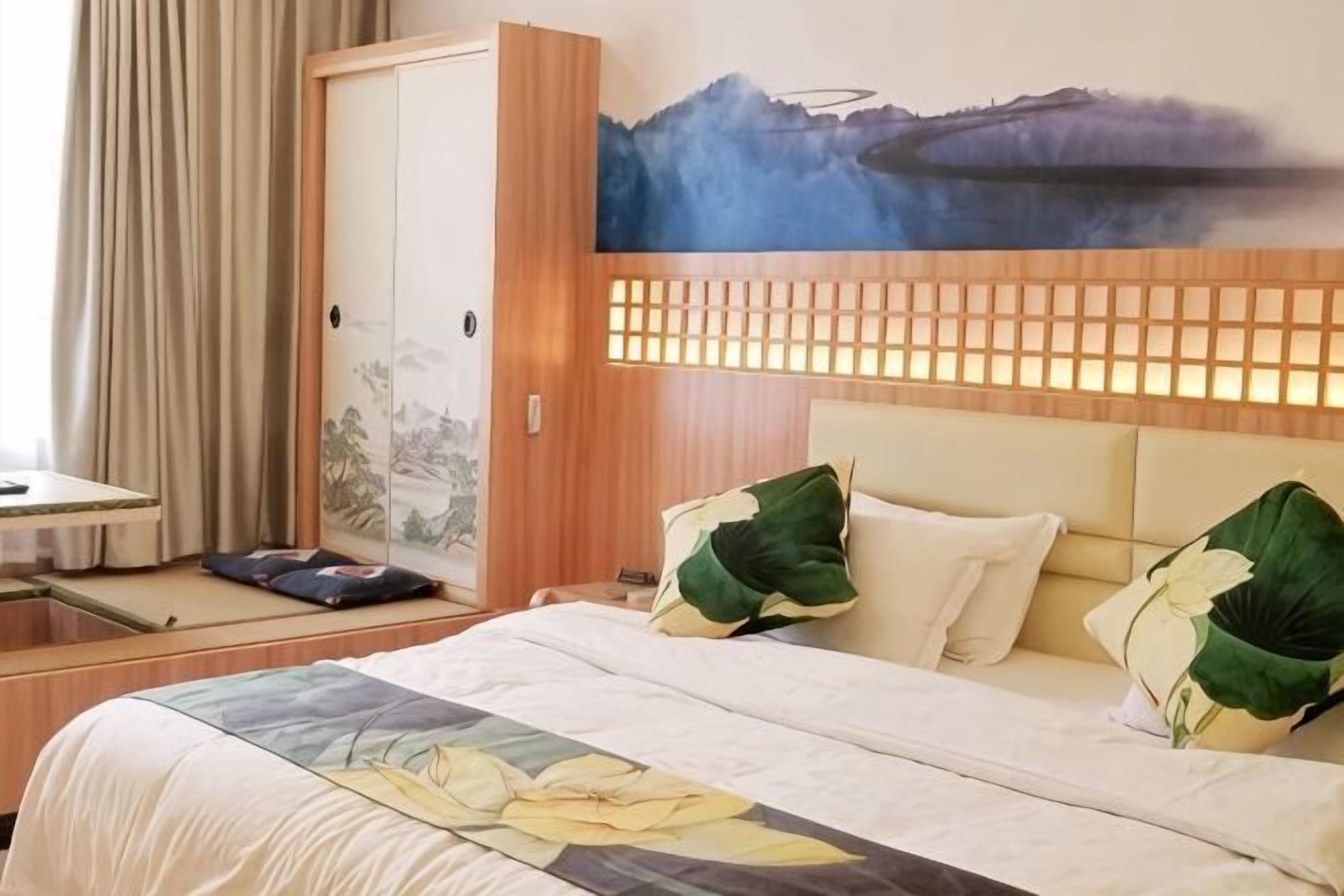 A hotel room with a bed, a desk, and a view of a mountainous landscape.