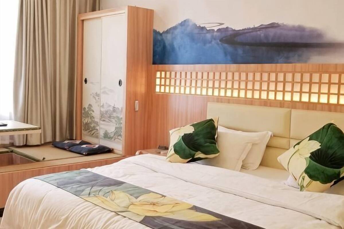 A hotel room with a bed, a desk, and a view of a mountainous landscape.