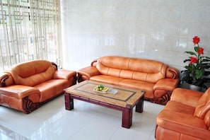 A living room with leather sofas, a coffee table, and a potted plant. - Shengcheng Jiayuan Hotel (Leishan)
